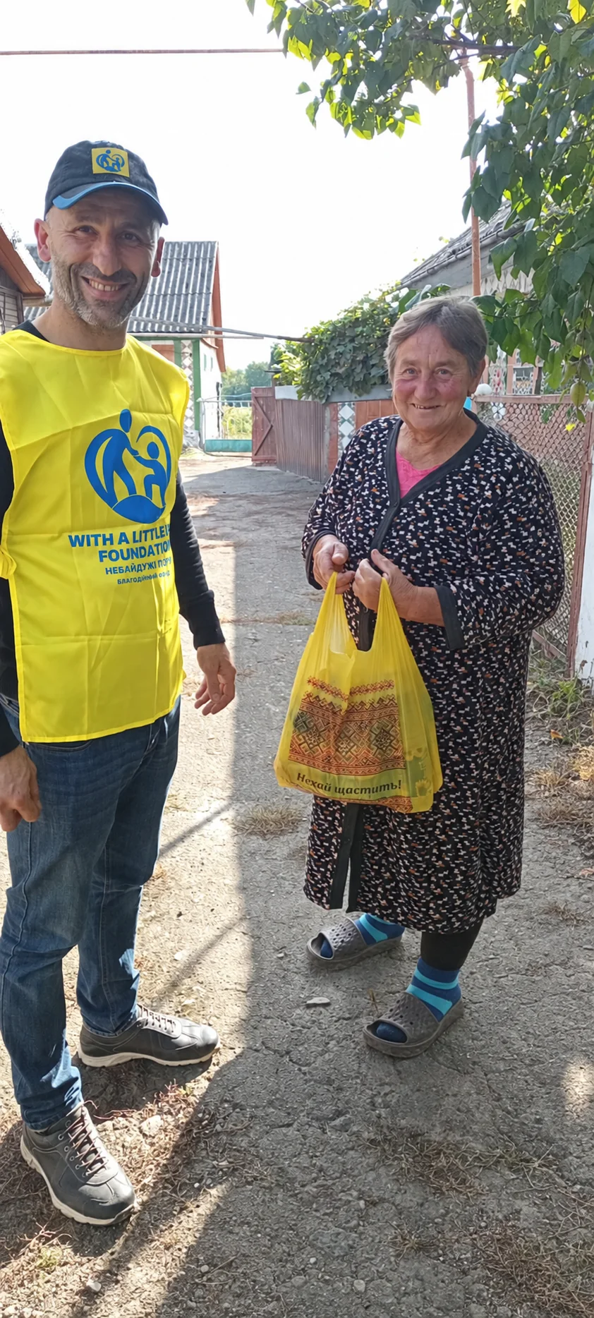 A team member and a woman with a bag standing together outdoors.